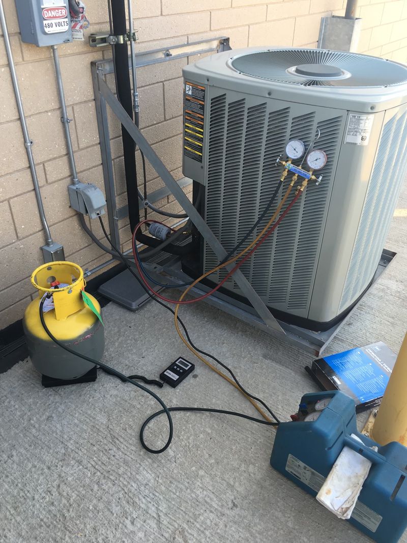 Technician gauges and refrigerant recovery machine connected to an outdoor air conditioning condenser