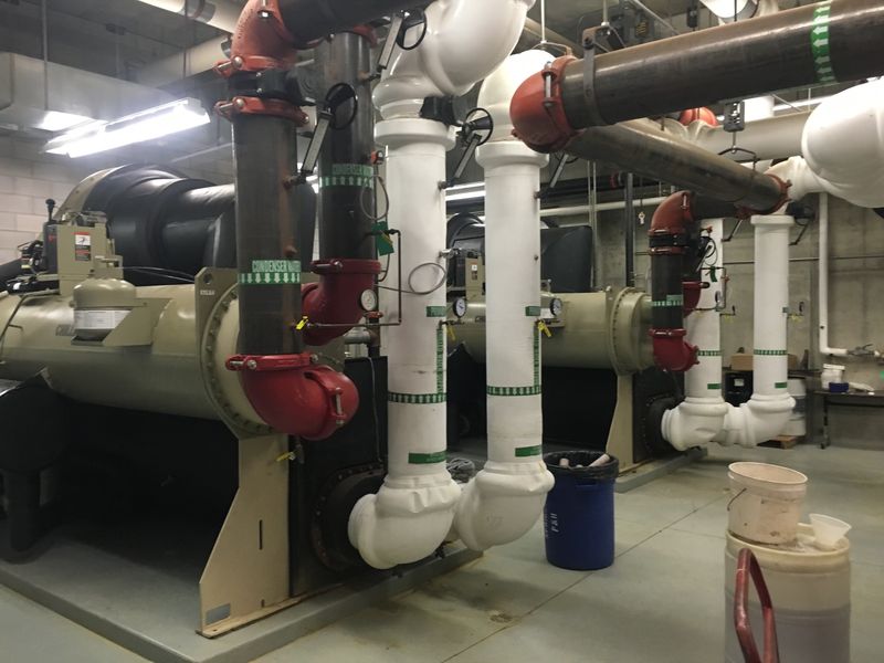 Commercial water-cooled chillers with condenser water and chilled water piping in a mechanical room