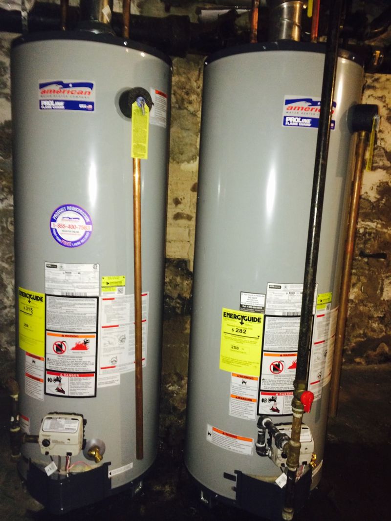 Two new gas tank water heaters installed side by side in a basement by Faith Mechanical